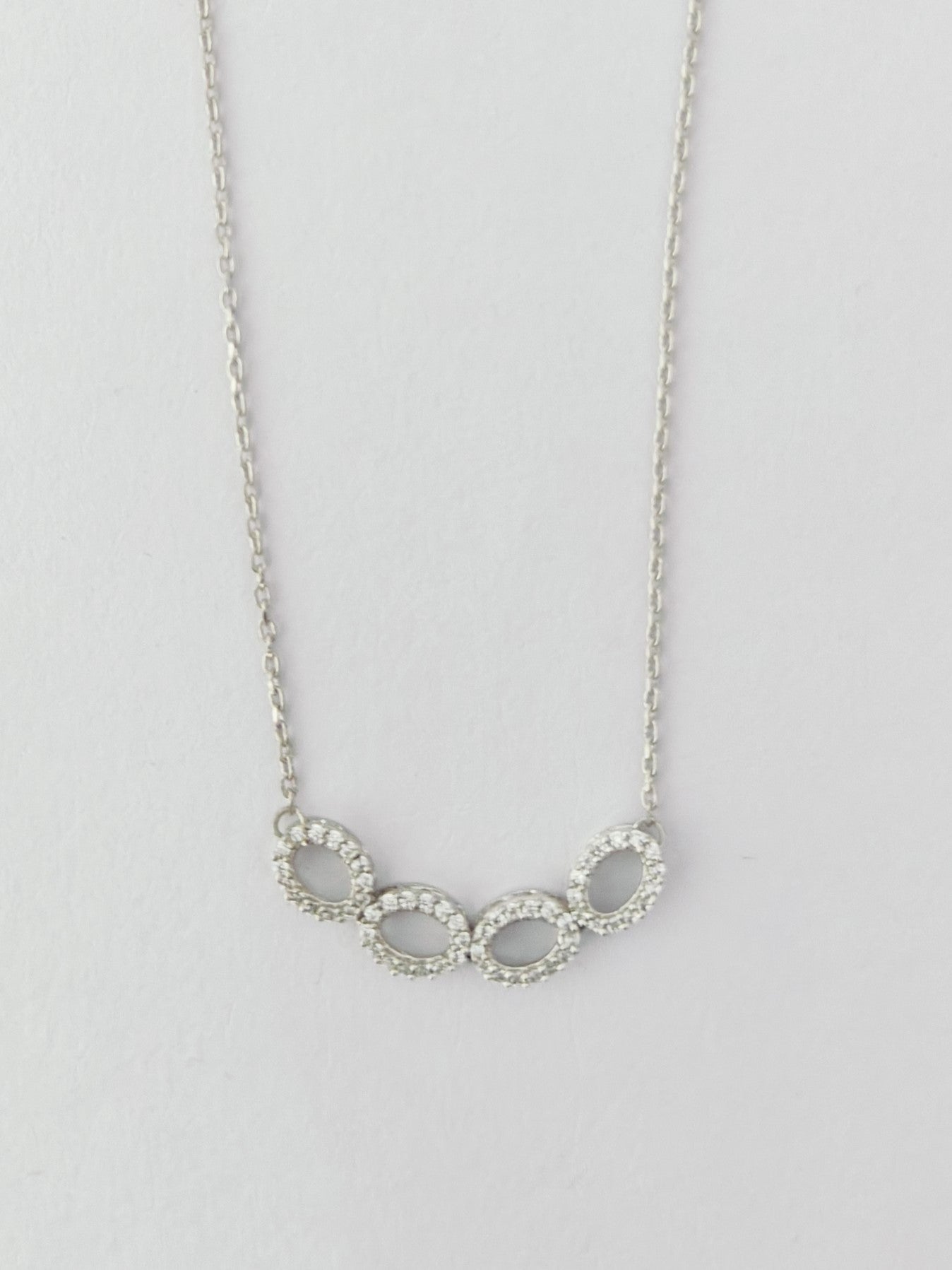 Silver necklace with interlocking rings on a light gray background